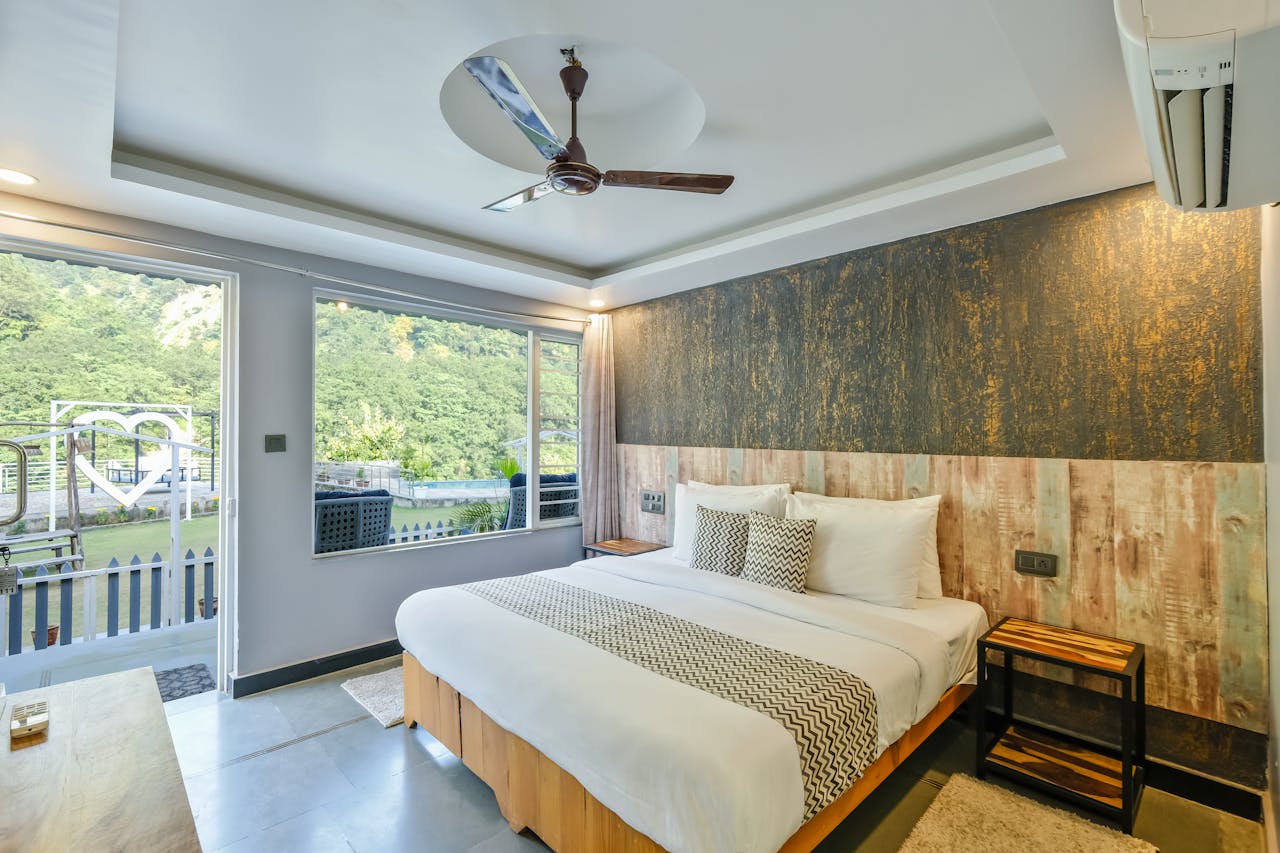 Modern hotel room in Rishikesh, India with a view of lush greenery from a large window.