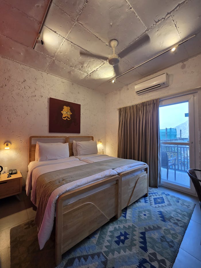 Warm hotel room interior with twin beds and balcony access at sunset.
