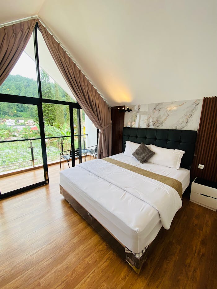 Inviting bedroom with balcony overlooking lush greenery and hills.