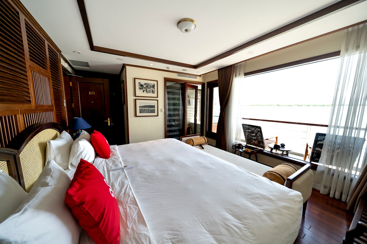 Spacious hotel bedroom with large windows and cozy decor overlooking an outdoor view, bright and inviting.